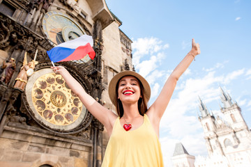 Obraz premium Young female tourist with czech flag in front of the famous astronomical clock in Prague