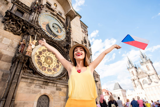 Young female tourist with czech flag in front of the famous astronomical clock in Prague