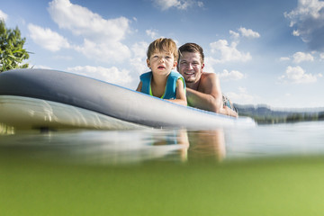 Father and son together having fun on a surfboard