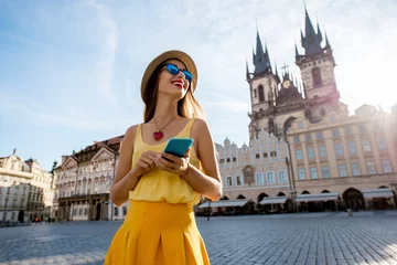 Papier Peint photo Prague Jeune femme en jaune marchant avec un téléphone intelligent sur la place de la vieille ville de Prague