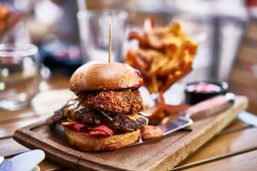 huge gourmet burger with onion rings and fries