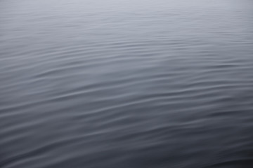 The texture of the silver surface of the water ripples with ligh