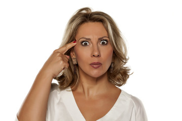 Fototapeta premium beautiful middle-aged woman with a questionable gesture and her finger to her forehead