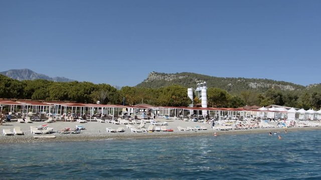 People are tanning on pebble and bathing on the beach on seashore of Mediterranean Sea