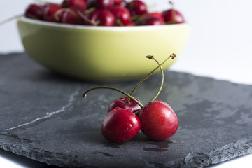 red cherries cutlery on dark stone background cherries in a bowl. Food and nutrition