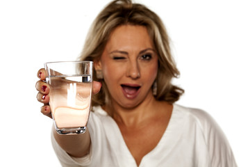 smiling middle-aged woman holding a glass with water and winking