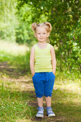 Fototapeta premium Cute little girl standing on a path in green park