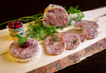 Homemade headcheese with dill and cranberries on a wooden board
