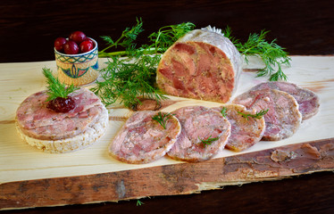 Homemade headcheese with dill and cranberries on a wooden board