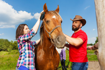 Fototapeta premium Happy young couple brushing mane of their horse