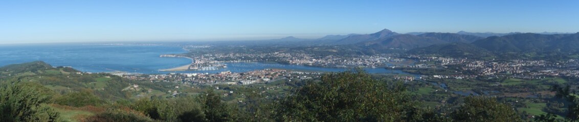 Fototapeta premium Panorámica de la desembocadura del río Bidasoa, de la costa del suroeste francés, los montes franceses y navarros, Hendaia y el aeropuerto de San Sebastián dentro del termino municipal de Fuenterrabía