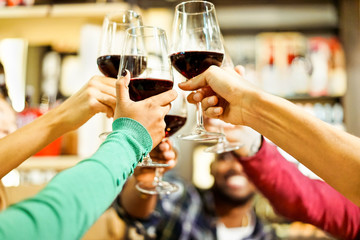 Group of students cheering with red wine at aperitif dinner bar