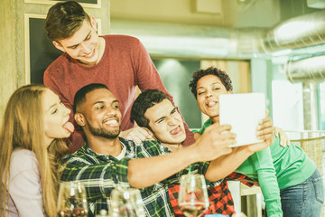 Group of cheerful friends taking selfie photo with tablet