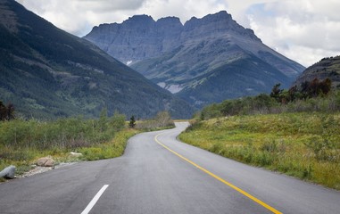 horizontal image of a highway winding its way through the mountains on a beautiful summer day.