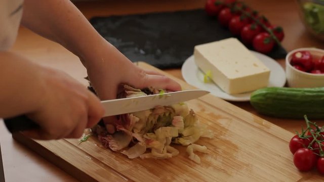 Female hands cutting tomato on the wooden cutting board