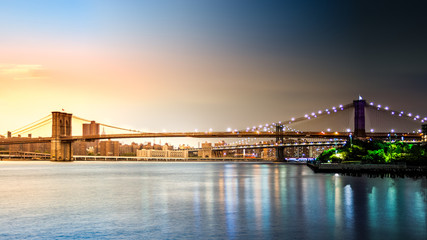 Obraz premium Composite image with Brooklyn Bridge transitioning from sunset to night on Pier2 park in New York City