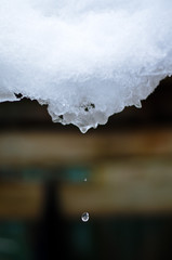 block of ice with a drop of water which falls to the ground