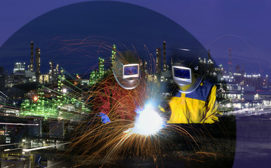 Oil refinery construction concept , The welder welding metal with many sharp sparks and Oil refinery plant at twilight background .