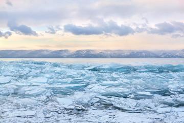 Naklejka na ściany i meble Field of blue transparent hummocks on the frozen Lake Baikal. Sunset sky.