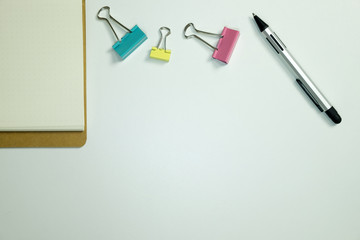 Office desk with clips paper, note book and pen