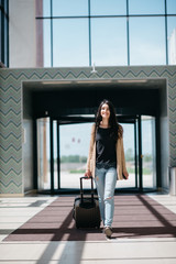 Fototapeta na wymiar young attractive girl with a suitcase goes on the terminal