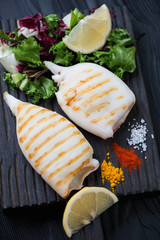 Grilled calamari served with a mix of fresh salad, lemon, spices