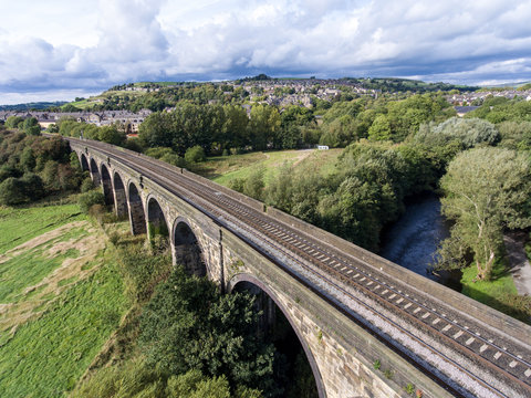 View from above: sideways railway bridge over green fields and village in the background