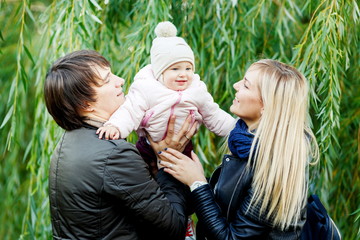 Happy couple with daughter in park near trees