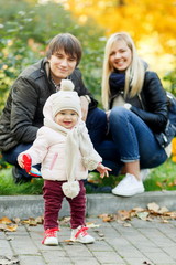 Fototapeta na wymiar Little girl walking in autumn park with her parents