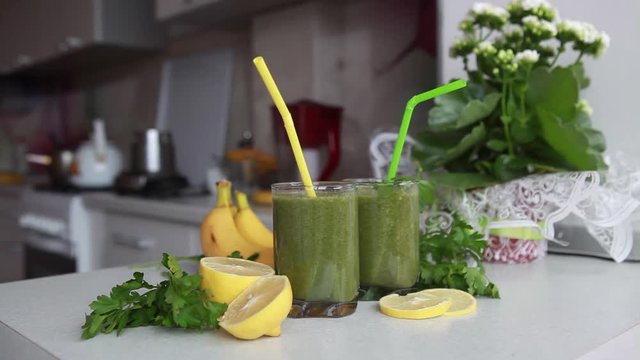 Two glasses of juice of spinach and parsley on a kitchen table