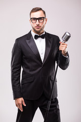 Naklejka premium Front-man in suit singing with the microphone and smile. Isolated on white background. Showman concept.