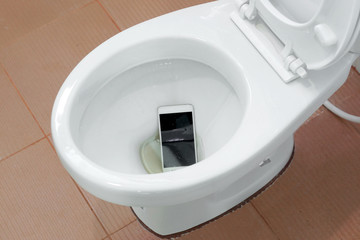 A white smartphone dropped into a toilet bowl