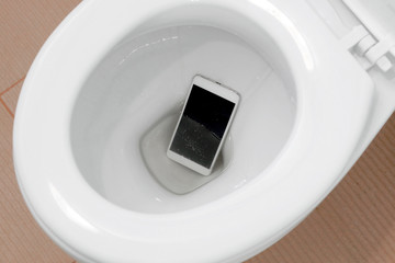 A white smartphone dropped into a toilet bowl