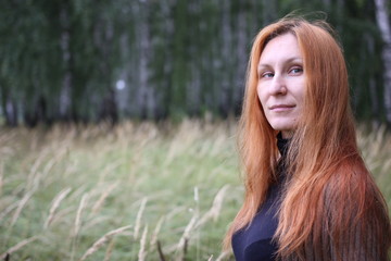 Attractive woman with red hair in the autumn forest