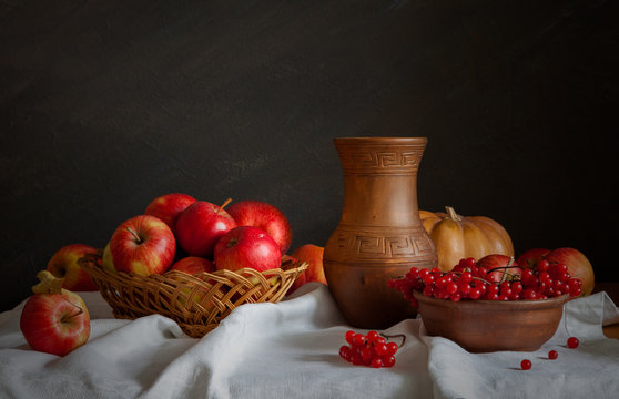 Still life in a rustic style. Red apples, viburnum and set of potteries.