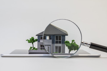 house miniature model on tablet pc and magnifying glass, searching or checking concept