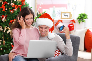 Young couple shopping online with credit card at home for Christmas