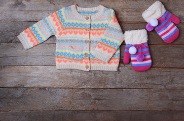 Obraz na płótnie Canvas Warm jacket and pair of colorful mittens on wooden background