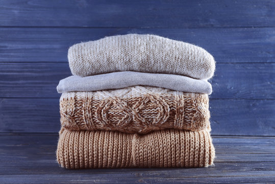 Stack of warm winter clothes on blue wooden background