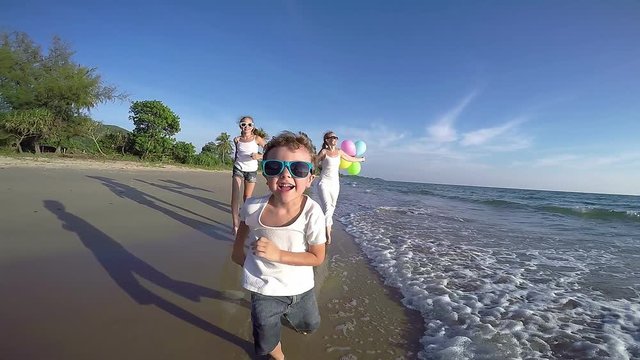 Happy family with balloons playing on the beach at the day time. Concept of friendly family. 