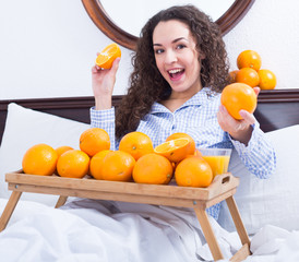 Obraz premium Positive girl with ripe oranges and glass of juice