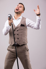 Naklejka premium Handsome singer gesture with hands on grey background.