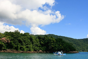 Fototapeta na wymiar Tropical coast with a single blue-white boat anchoring