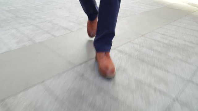 Close crop of man’s feet walking in city (steadicam shot)