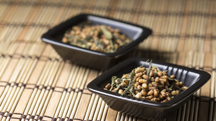 Genmaicha tea in black plate on bamboo tablecloth
