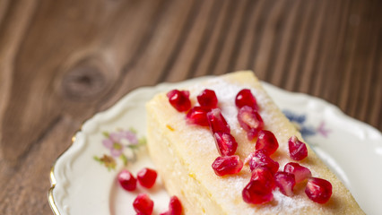 Cheesecake with pomegranate seeds on wooden table