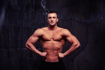 Fototapeta na wymiar Handsome bodybuilder with toned muscular body posing shirtless