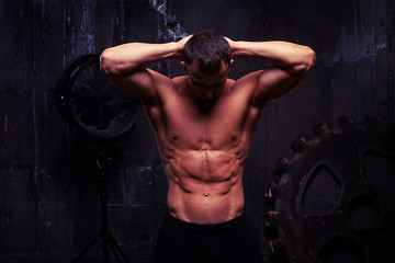 Fototapeta na wymiar Sexy muscular man standing with hands behind his head, his abs p