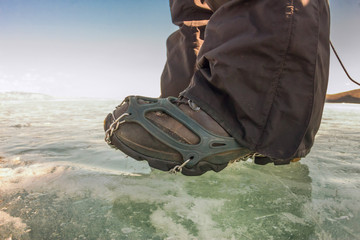 Human legs in hiking boot in ice crampons on the texture Baikal