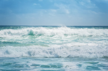 Fototapeta na wymiar blue ocean waves and blue cloudy sky